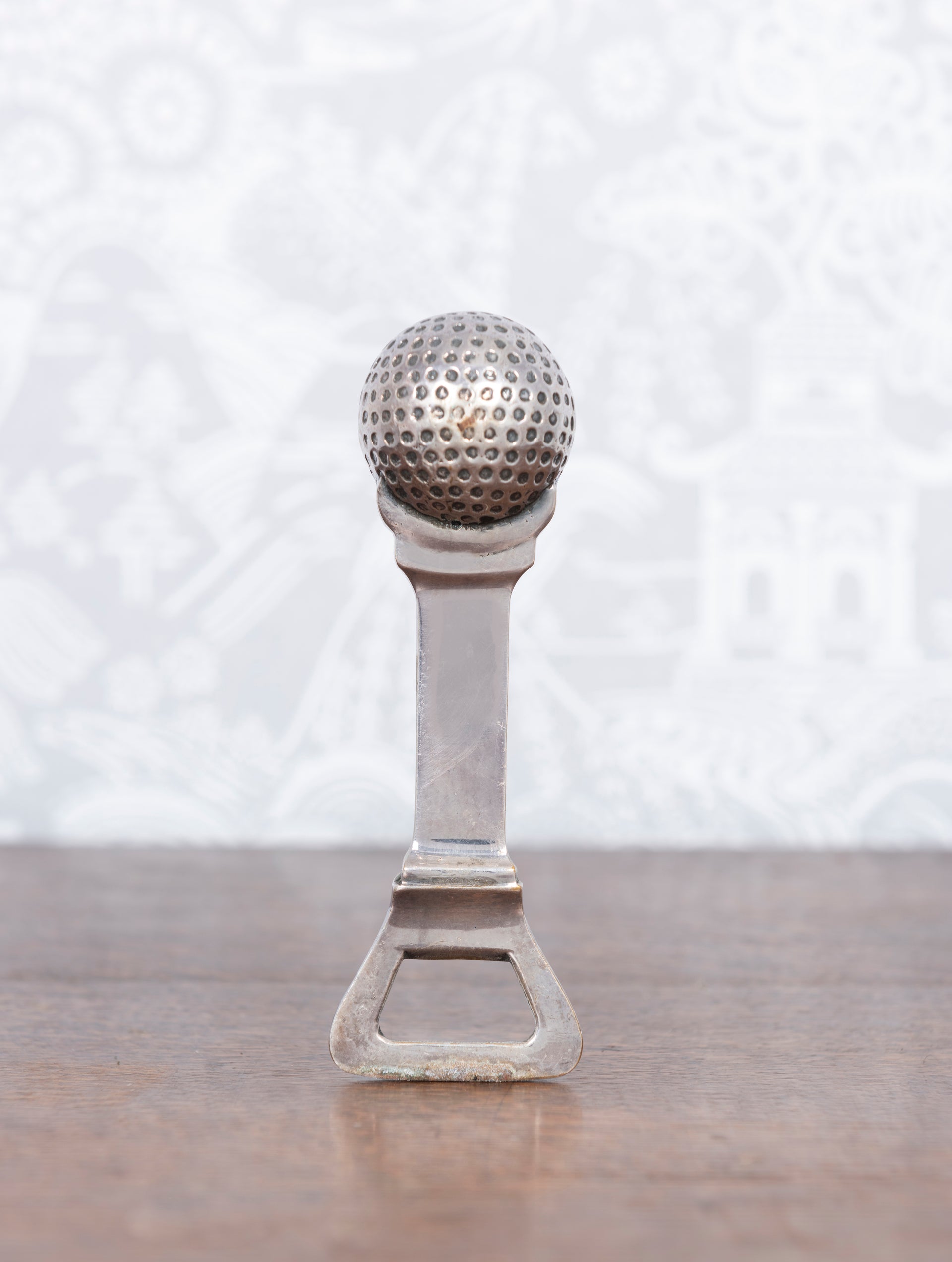 A vintage Spanish metal bottle opener in the form of a golf ball